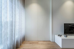 Ein modernes Zimmer mit Holzboden, weißer Wand und Fernseher auf einem weißen Schrank.