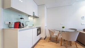 Een moderne keuken met een rode blender, een tafel met glazen blad en een witte bank.