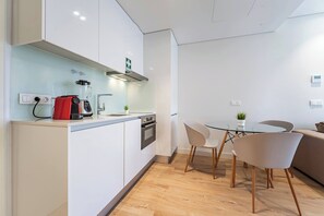 Eine moderne Küche mit einem roten Mixer, einem Glastisch und einem weißen Sofa.