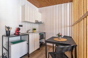 A compact kitchen with a microwave, toaster, and cabinets, a dining table with chairs, and a wooden ceiling. - Wake up with the Sea Breeze- House with pool AP2 (Lavra)