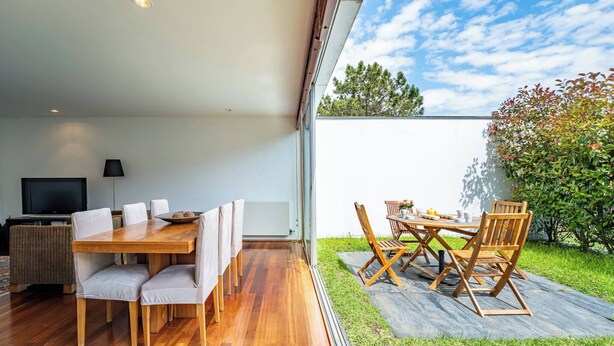 Un comedor interior con una mesa y sillas de madera, un televisor y un sofá.