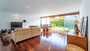 Una sala de estar moderna con un sofá, televisor, mesa de comedor y sillas.