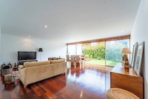 Una sala de estar moderna con un sofá, televisor, mesa de comedor y sillas.