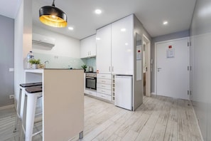A modern kitchen with white cabinets, a built-in oven, and a refrigerator. - Oporto Wine Cellars Flat With Terrace (Vila Nova de Gaia)
