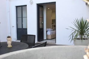 A room with a bed, a chair, a potted plant, and a door leading to another room. - Oporto Wine Cellars Flat With Terrace (Vila Nova de Gaia)