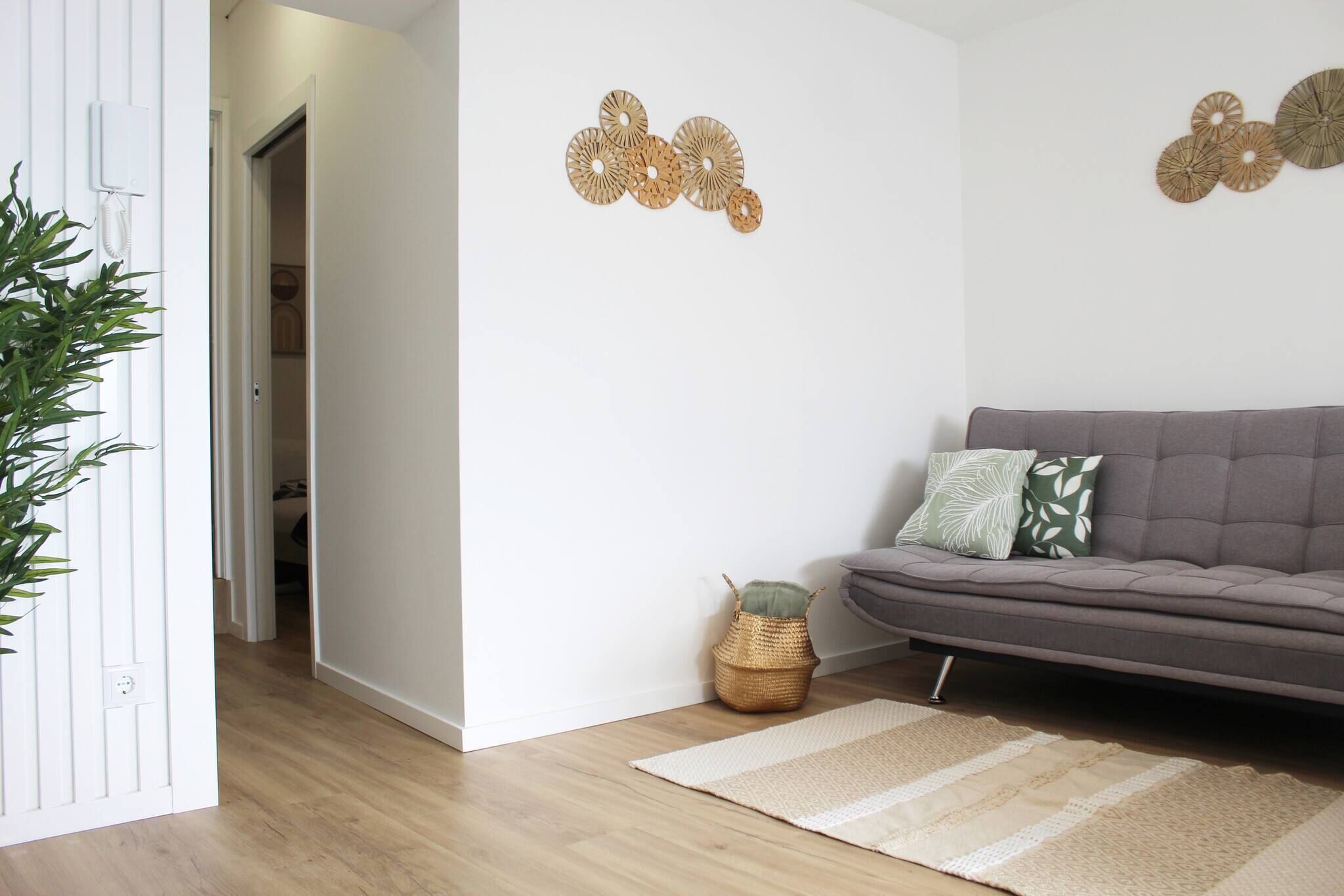 A modern living room with a grey sofa, a woven basket, and decorative wall art.