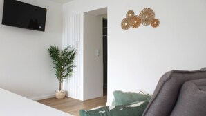 A modern living room with a flat-screen TV, a potted plant, and decorative wall art. - Valbom Hideaway Light, Style and Peace (Valbom)