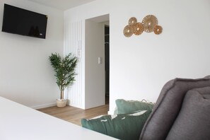 A modern living room with a flat-screen TV, a potted plant, and decorative wall art. - Valbom Hideaway Light, Style and Peace (Valbom)