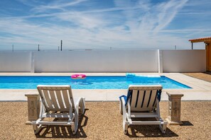 A swimming pool with two white lounge chairs and a pink float. - Wake up with the Sea Breeze- House with pool AP1 (Lavra)
