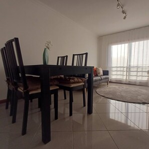 A dining area with a table, chairs, a vase with flowers, a sofa, and a large window with curtains. - Perfect Oporto with Terrace and Good Vibes (Oporto)