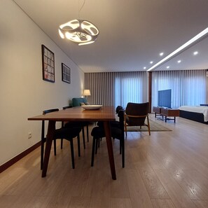 Ein modernes Hotelzimmer mit Essbereich, einem Bett und einem großen Fenster mit Vorhängen.