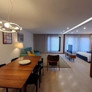 Ein Hotelzimmer mit Essbereich, einer Couch, einem Fernseher und einem Bett.
