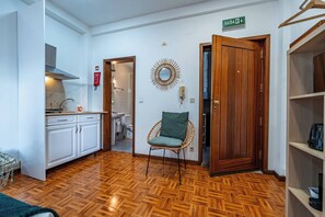 Ein Zimmer mit Fischgrätparkett, einem Korbsessel, einer Holztür und einem Spiegel an der Wand.