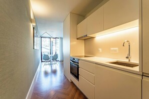 Eine moderne Küche mit Einbauofen, Spüle aus Edelstahl und Fenster mit Blick auf die Stadt.