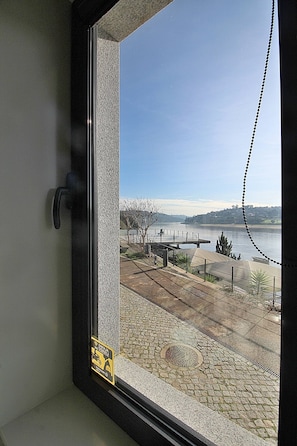 A window with a view of a paved area, a body of water, and distant hills. - RestOnDouro Oporto Studio (Valbom)