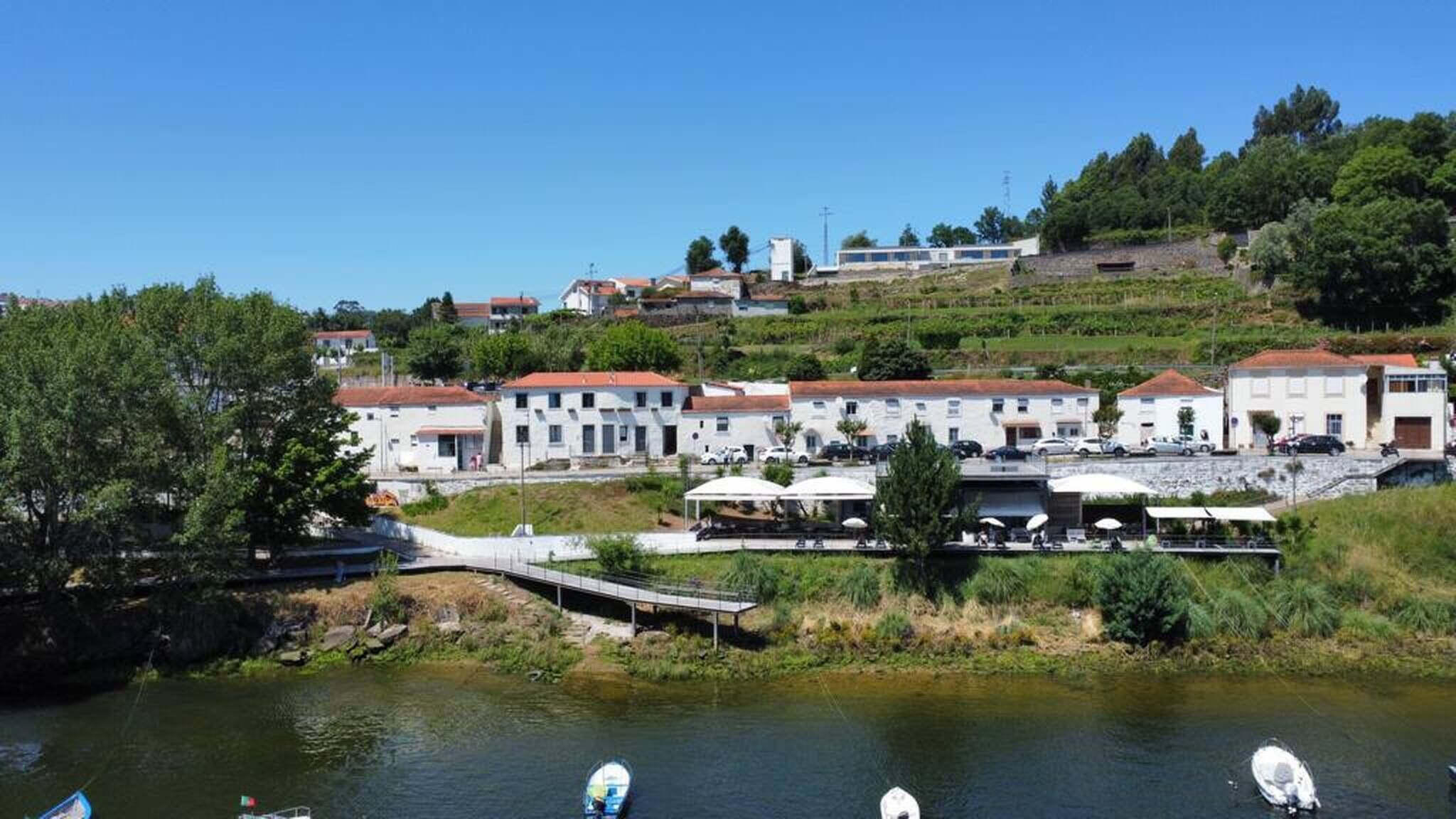 A riverside hotel with white buildings, a bridge, and boats on the water.