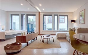 Ein modernes Wohnzimmer mit einer Couch, einem Fernseher, einem kleinen Tisch und einem Sessel.