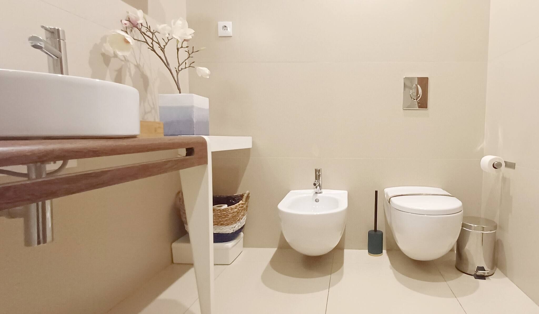 A bathroom with a sink, bidet, toilet, and a small decorative plant.