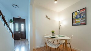 Un comedor con una mesa, sillas, una planta y una obra de arte en la pared.