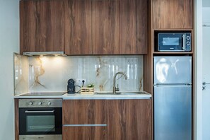 Eine Küche mit Holzausstattung, einem Edelstahlkühlschrank, einer Mikrowelle und einem Backofen.