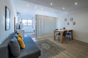 Ein modernes Wohnzimmer mit einer Couch, einem Esstisch und Blick durch eine Schiebetür.