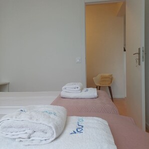 A hotel room with two beds, a chair, and a door. - Your Home in Porto 1480 Style and Confort (Oporto)