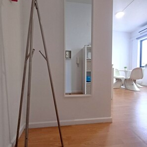 A room with a wooden floor, a white wall, and a mirror reflecting a white cabinet and a chair. - Your Home in Porto 1480 Style and Confort (Oporto)
