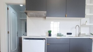 Ett modernt kök med en inbyggd diskmaskin, mörka köksskåp, ett fönster och en diskho.