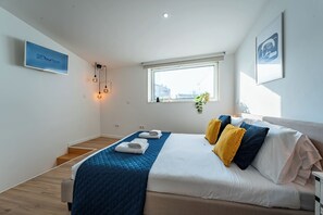 Una habitación de hotel moderna con cama, televisor, ventana y escalera.