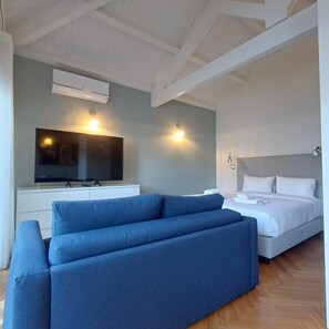 Ein modernes Hotelzimmer mit einem großen Bett, einer Sitzecke, einem Flachbildfernseher und zwei Wandleuchten.