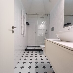 Ein modernes Badezimmer mit Duschkabine aus Glas, einem weißen Waschbecken und einem Musterboden.