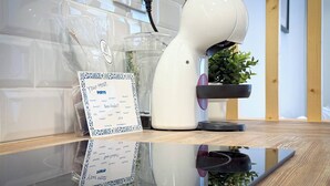 Un robot blanc, une plante en pot et un menu affiché sur une surface réfléchissante.