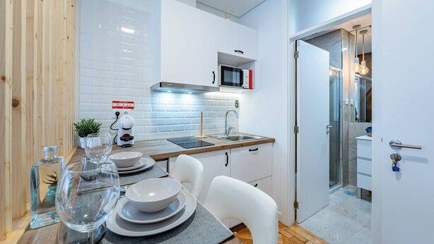 Une cuisine moderne avec des meubles blancs, un four à micro-ondes et un évier.