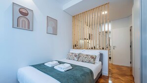 Une chambre d’hôtel avec un lit, une cloison en bois et des œuvres d’art accrochées aux murs.