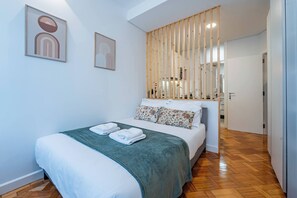 A hotel room with a bed, a wooden partition, and artwork on the walls. - New Alegria in Town 2 (Oporto)