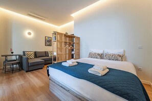 Ein modernes Schlafzimmer mit Bett, Sofa, Schreibtisch und Kleiderschrank.