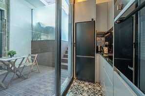 Eine moderne Küche mit einem schwarzen Kühlschrank, einer Kaffeemaschine und einer kleinen Arbeitsplatte.