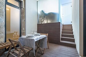 Ein Essbereich mit einem Tisch für zwei Personen, einem Holzstuhl und einer Treppe.