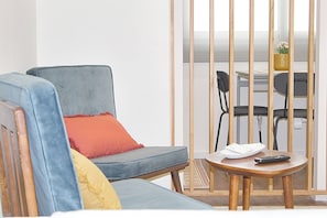 Een moderne woonkamer met een grijze bank, een klein houten tafeltje en een zwarte stoel.
