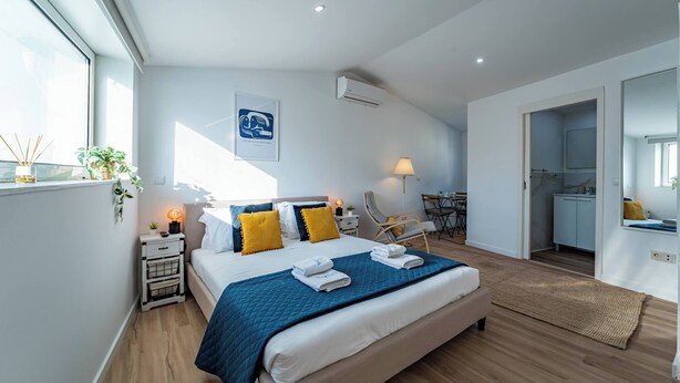 Una camera da letto moderna con un letto grande, comodini, una scrivania e vista sulla cucina.