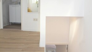 Un corridoio con pavimento in legno, una porta bianca e un piccolo armadietto.