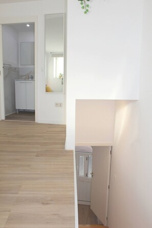 Ein Flur mit Holzboden, einer weißen Tür und einem kleinen Schrank.