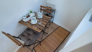 Un'area pranzo accogliente con un tavolo di legno, quattro sedie, una panca imbottita e una rastrelliera in metallo con piatti.