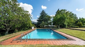 A rectangular swimming pool with a tiled deck, surrounded by grass and trees. - Casa das Pintoras Garden and Pool (Vile)