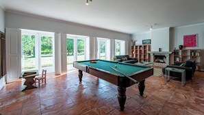 A spacious room with a pool table, a fireplace, and a bookshelf. - Casa das Pintoras Garden and Pool (Vile)