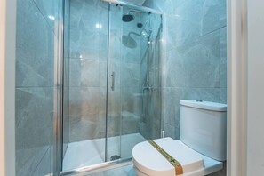 Une salle de bain moderne avec une douche à parois de verre, des toilettes blanches et un rideau de douche.