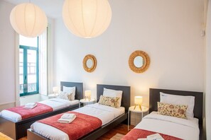 A hotel room with three beds, each with a red blanket and white pillows, and two wall-mounted lamps. - Casa Romero - Family & Friends, Surf & Beach (Matosinhos)