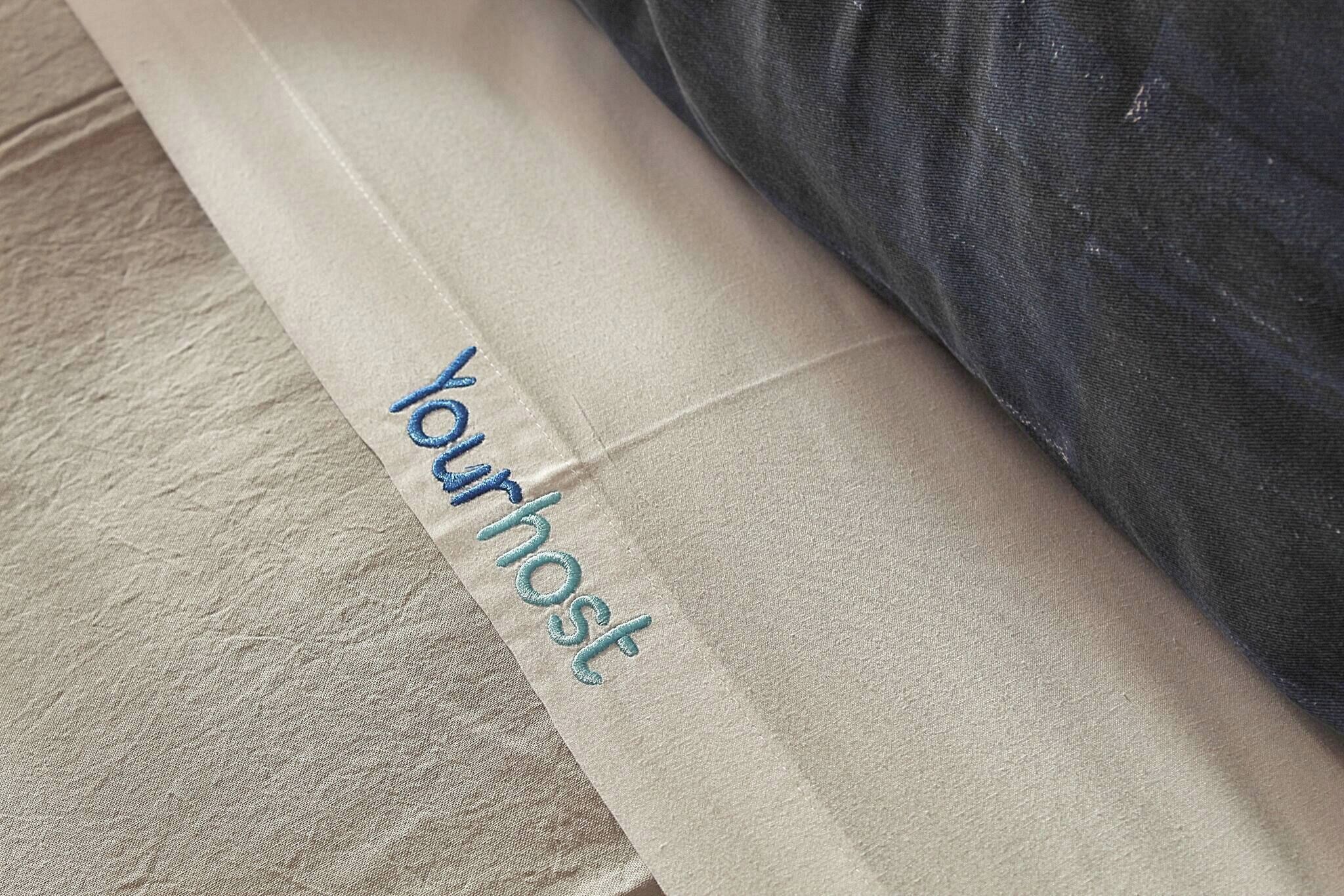 A pillow with the word 'Yourhost' embroidered on it.