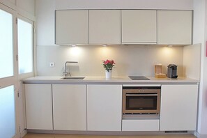 Eine moderne Küche mit weißen Schränken, einem eingebauten Backofen und einer kleinen Arbeitsfläche.