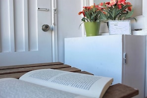 Ein Zimmer mit Holztisch, geöffnetem Buch, Zimmerpflanze im Blumentopf und einem Schild an der Tür.